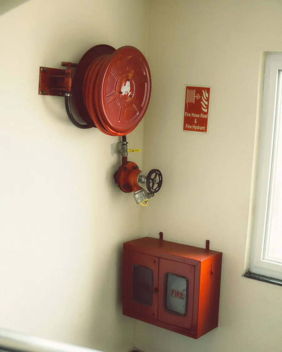 Wall-mounted fire hose reel, hydrant valve and hose cabinet in a building stairwell